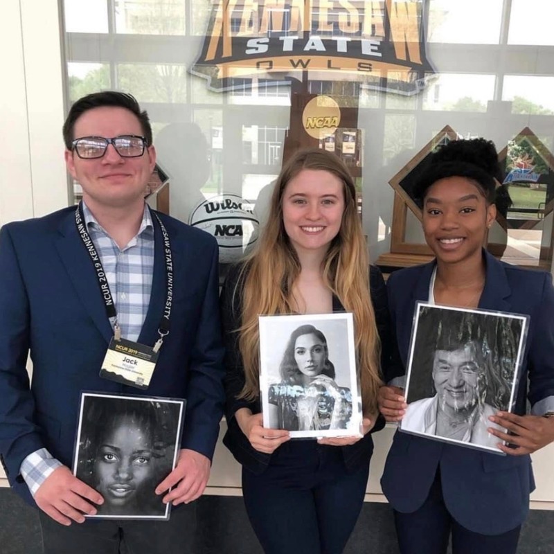 Research group holding photos at NCUR